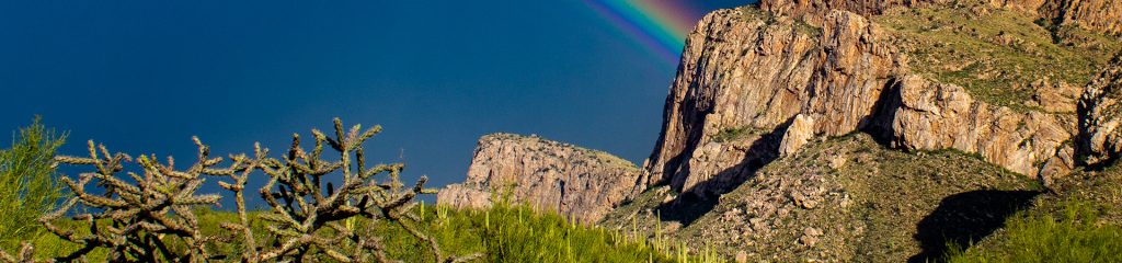 A rainbow in the sky above the Linda Vista hiking trail, looking at Push Ridge in the Catalina Mountains north of Tucson, Arizona.